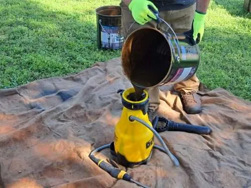 20230615_093115 Pouring Stain into a pump sprayer to prepare it for staining.