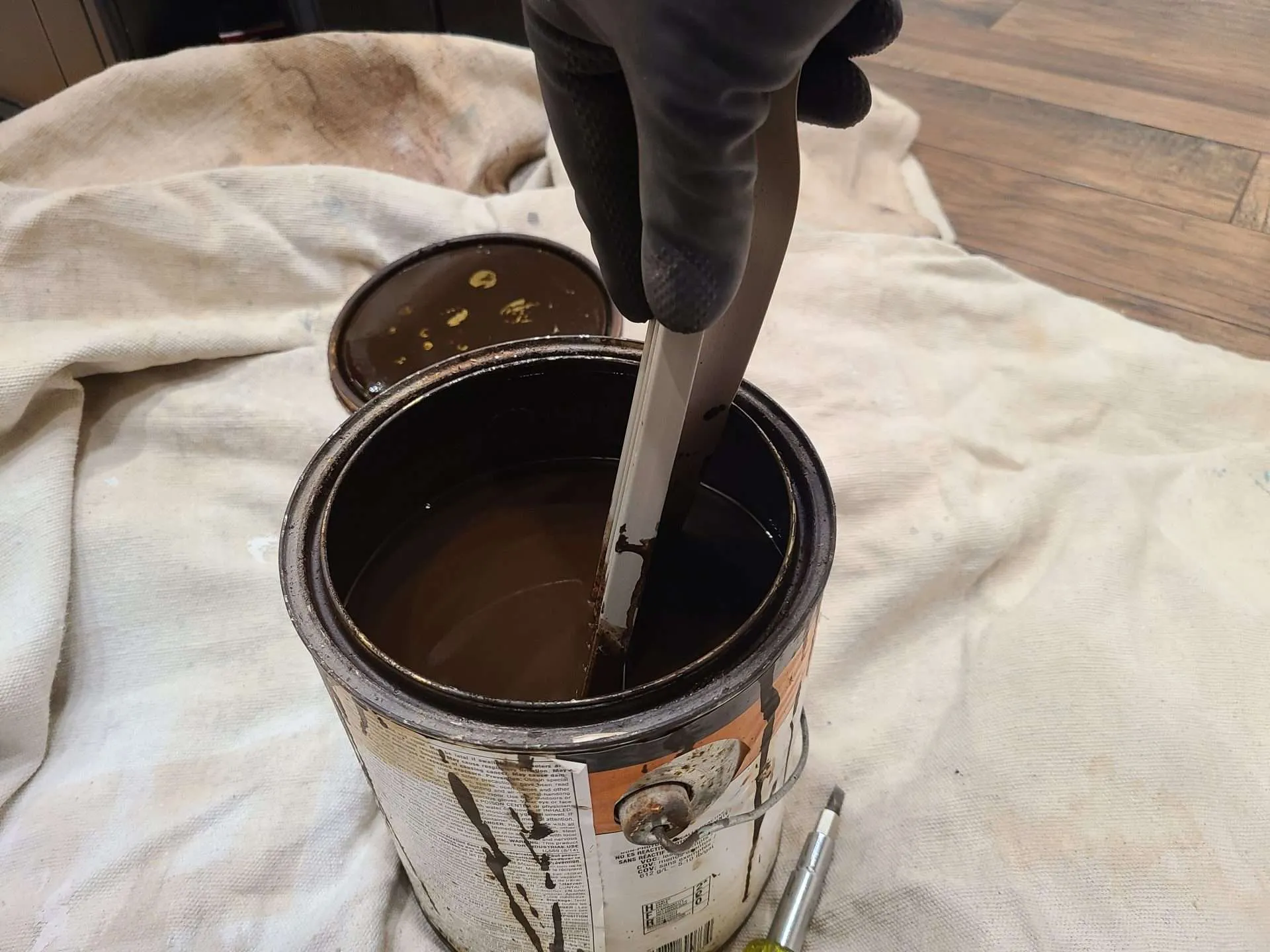 20241223_093954 Stirring wood stain in a can before touching up nicks in stained wood trim