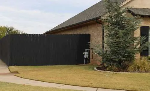 Black Fence Stain a wooden fence with a black oil-based fence stain.
