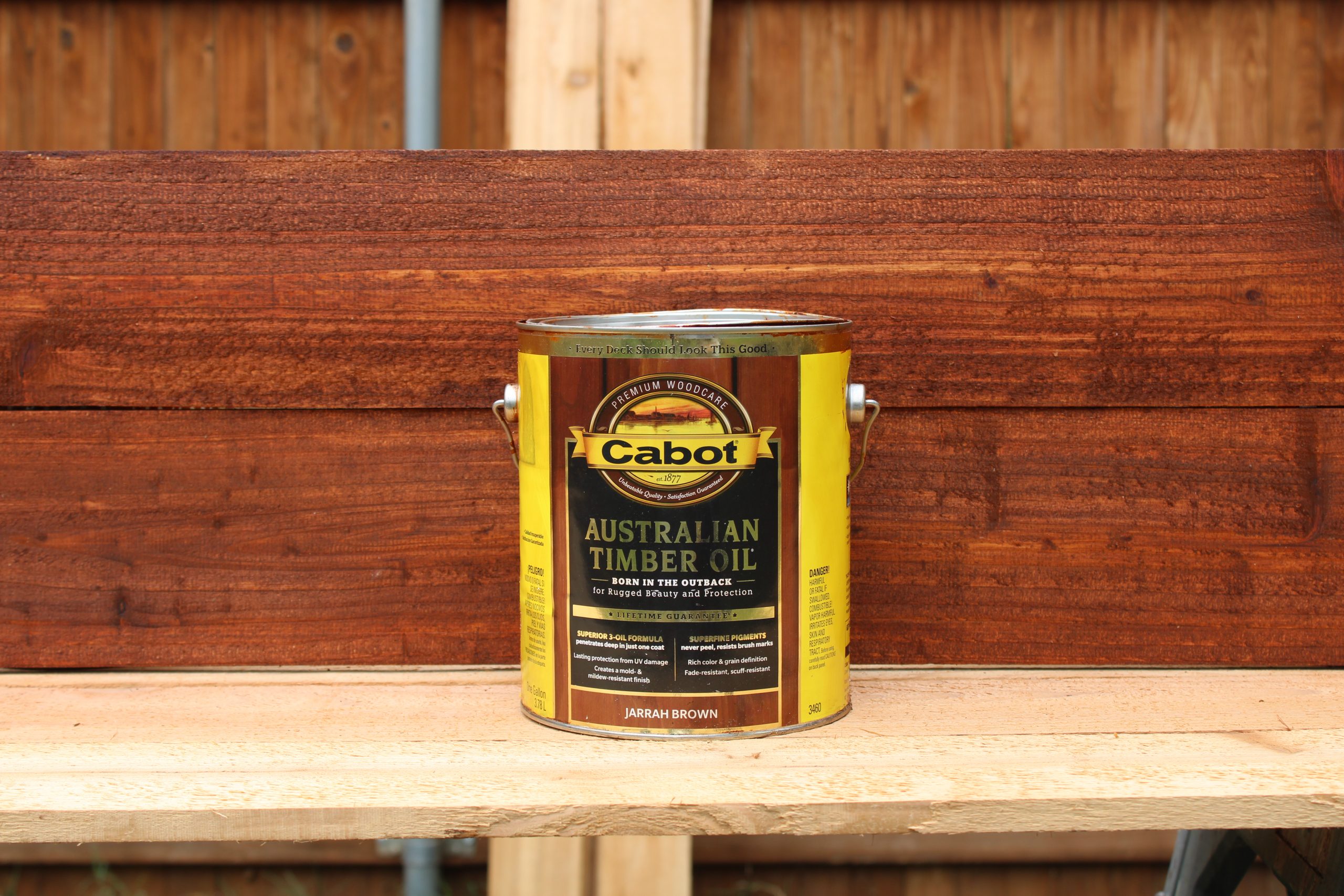IMG_0743 a can of Cabot Australian Timber Oil fence Stain in front of some wooden fence boards.