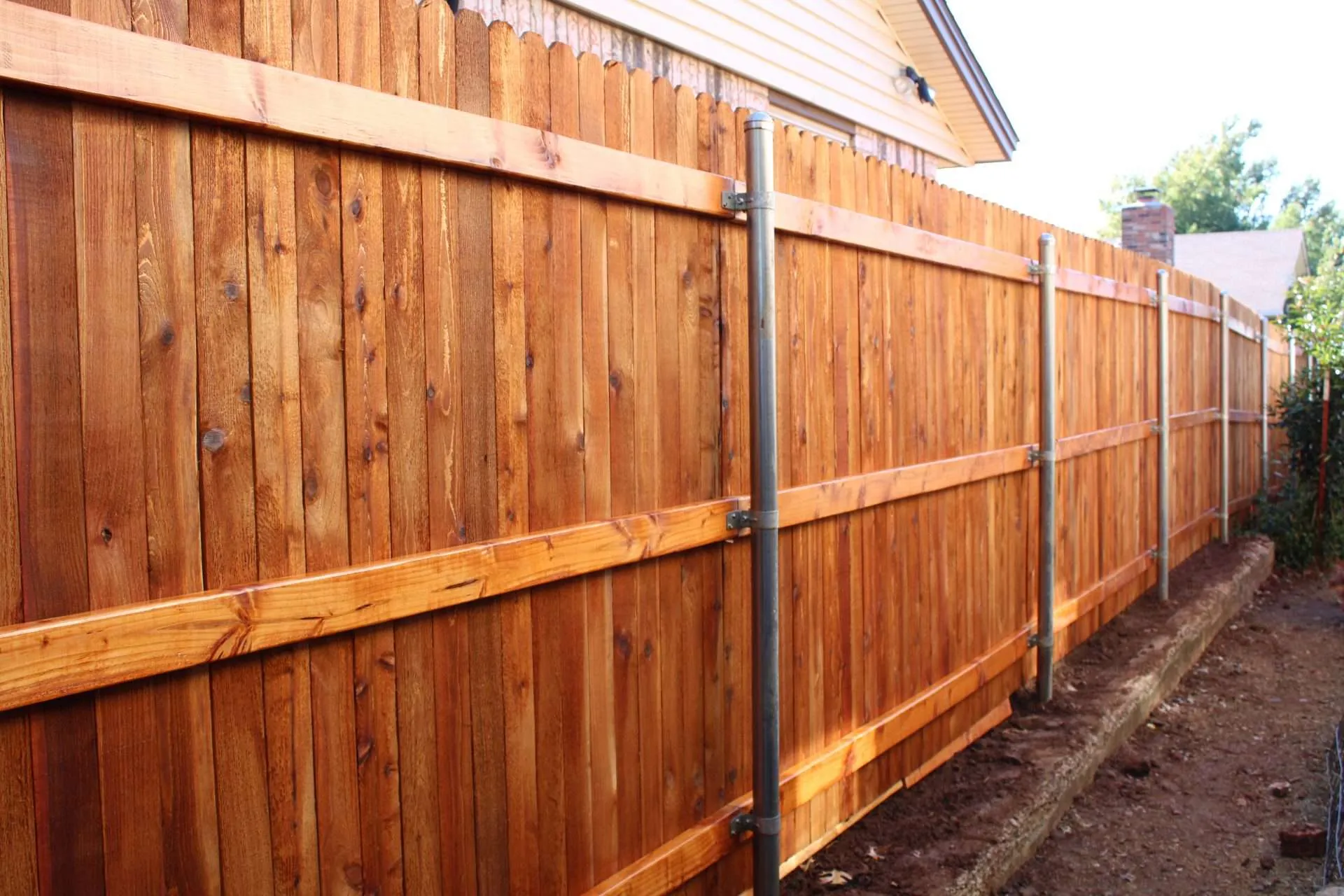 IMG_0875 picture showing the back side of a fence with metal poles that is stained.
