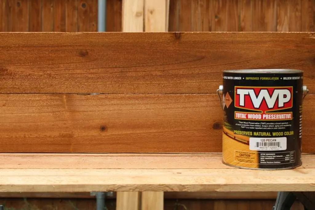 Total Wood Preservative Stain a can of twp wood stain in front of two boards that were stained with the pecan color.